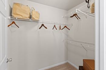 A walk in closet in a bedroom with a door open